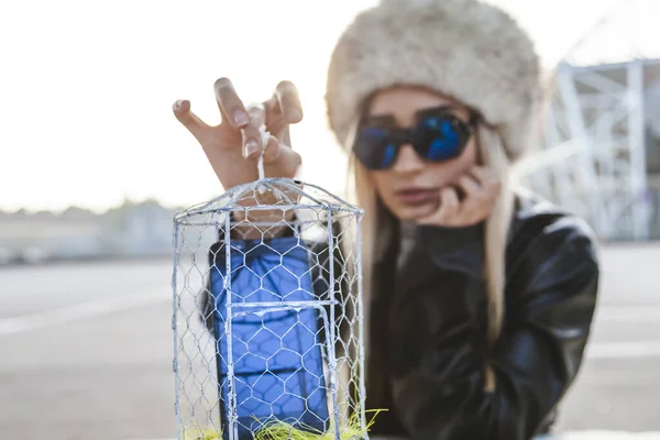 Ung söt kvinna medan du visar en mobiltelefon inuti en metall cag — Stockfoto