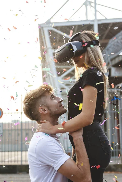 Hermosa pareja enamorada divirtiéndose en una lluvia de colorido confet — Foto de Stock