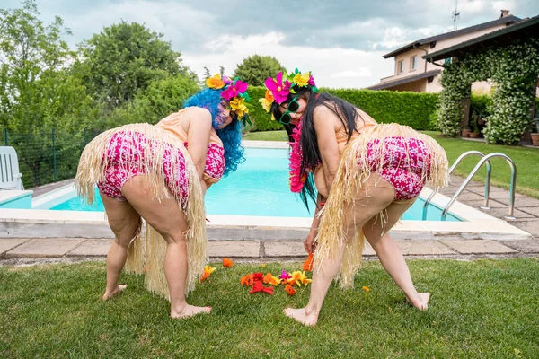 Duas Amigas Trajes Havaianos Estão Colhendo Flores Gramado Frente Piscina — Fotografia de Stock