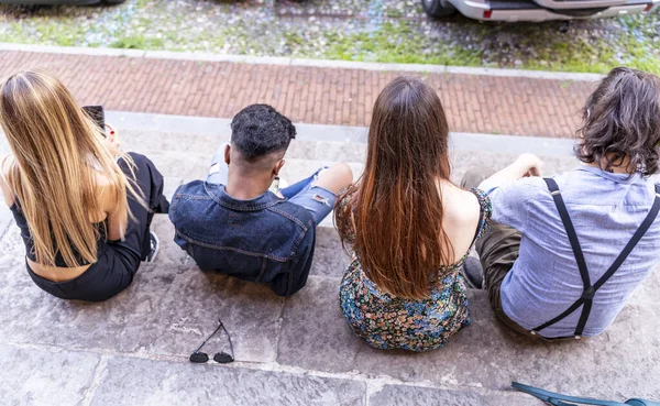 一群多种族朋友坐在大理石楼梯上 用智能手机在社交网络上分享内容 — 图库照片