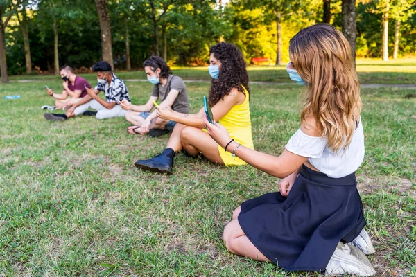 Grupo Amigos Multirraciais Sentados Parque Público Livre Usando Telefones Inteligentes — Fotografia de Stock