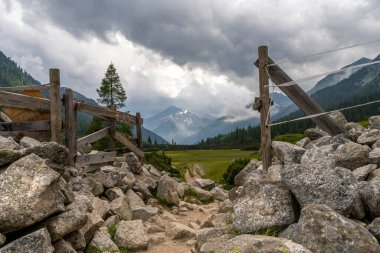 Tahta kapıdan geçen küçük bir patika. İtalyan Dolomitlerinin panoramik görüntüsü