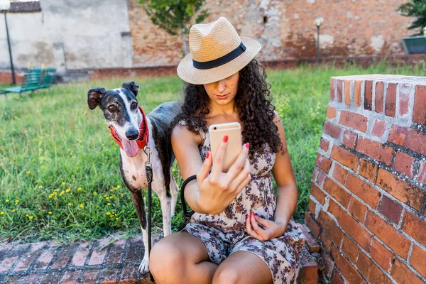 若い女性がスマートフォンを使って犬と遊んでソーシャルネットワーク上でコンテンツを共有しています — ストック写真