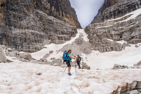 2人の経験豊富な女性ハイカーがイタリアのドロミテの雪の谷に登っています — ストック写真