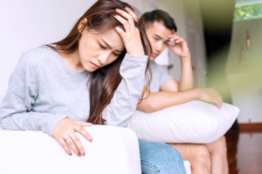 Mutsuz genç bir kadın erkek arkadaşıyla kanepede otururken oturma odasında kavga ettikten sonra konuşmama stresi. Kocasının koltukta oturduğunu düşünen üzgün bir kadın. İlişki sorunu aşığı kavramı.