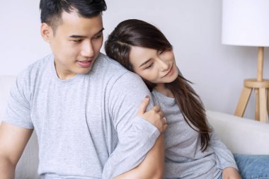 Neşeli bir gülümseme. Oturma odasında rahatlarken erkek arkadaşını kucaklayan genç bir kadın. İlişki birlikteliği çift aşk kavramı.