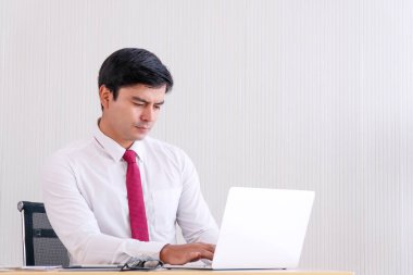 Ofisteki masada otururken verileri analiz eden bir iş adamı. İş yerinde dizüstü bilgisayarda yazarken dijital cihazlar ve programlar kullanarak çalışan bir adam. Başarılı ve teknoloji kavramı.