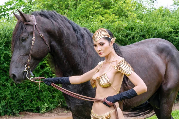 Seksi genç kadın vücudu ince giyer moda elf fantezisi doğada siyah at ile dolaşır.