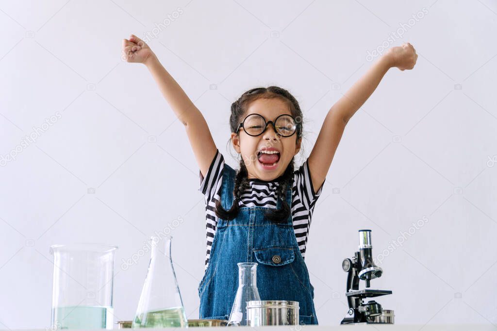 Little 6s cute girl wear glasses happy raise arms with microscope, laboratory bottle and water experiment study scientists while learning success at school. Education science concept.