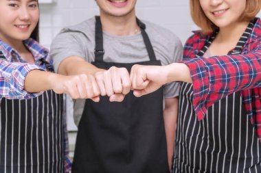 Grup arkadaşları önlük takıyor, yumruklarını birleştirip mutfakta duruyorlar, kardeşlik içindeler. Mutluluğu ve yıldönümünü, yeni yılı ya da doğum gününü kutluyorlar. Arkadaşlık kavramı. 