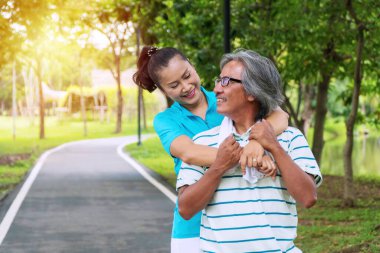 Yaşlı çift egzersiz konsepti. Yaşlı adam ve kadın parkta birlikte egzersiz yaptıktan sonra rahatlar. Mutlu bir gülümseme. Yaşlı kadınlar el ele tutuşuyorlar. Kocasına sarılıyorlar..