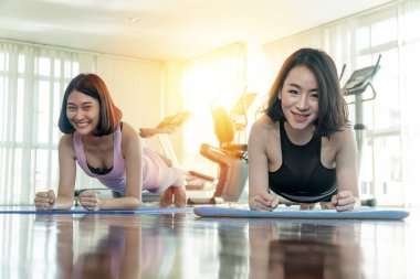 Çekici, genç, neşeli Asyalı kadın spor giyer spor giyer ve spor salonunda kol kola girerler. Spor salonunda vücut geliştiren iki fitness, zayıf bayan arkadaş. egzersiz konsepti.
