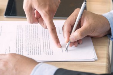 Belgeleri imzalamak için elinde kalem tutan bir iş adamı. Ortaklık eli, başarıdan sonra imzalanacak bir belge formunu işaret ediyor.