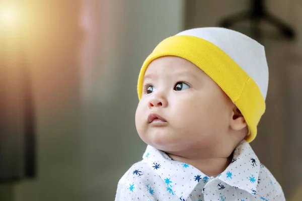 Sevimli küçük bebek bir şeye bakarken kumaş şapka takıyor. Yumuşak, sıcak bir tonda birini beklerken çocuksu yüz ifadesini kapat..
