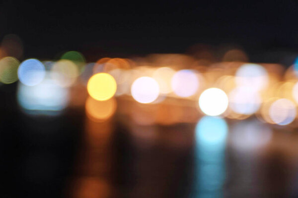 Abstract colorful blurred bokeh soft bright circle light on nightlife at river. Wallpaper and background. Defocused light night landscape with reflection on river.