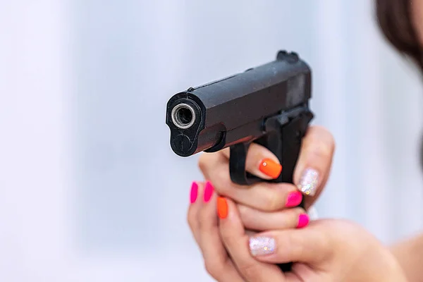 Woman holding gun in her hand at home. Focus hand of young women using black gun protection from danger gesture killer.