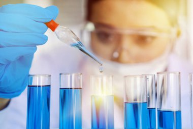 Araştırmacılar modern bir laboratuvarda insanların sağlığını korumak ve korumak için iyi yollar buluyorlar. Laboratuvarda bilimsel test tüpüyle çalışan genç bilim kadını..