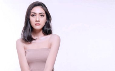 Beyaz arka planda izole edilmiş gülümseyen genç bir kadın. Asyalı mutlu kız kameraya bakıyor. Cilt bakımı stüdyo beyazında sağlıklı genç kadınlarla karşılaşıyor.