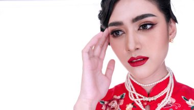 Genç bir kadın, gri arka planda izole edilmiş fotokopi alanı olan kırmızı bir elbise giyiyor. Hanımefendinin güzel bir yüzü ve güzel bir cildi var. O, kırmızı ruj sürdü. Çin Yeni Yıl Konsepti.