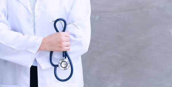 Concept of Healthcare And Medicine. Young woman Doctor's hand holding stethoscope on grey background with copy space.