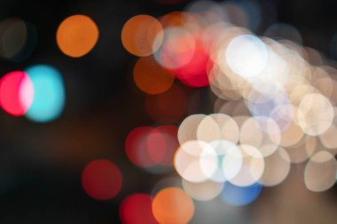 Soyut araba ışıkları caddedeki trafiği bozuyor. Gece ışıklarının bulanıklığı yolda kaybolur. Arka plan olarak şehrin rengarenk ışıklarını kullan.