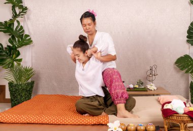 Thai masajını kabul et. Güzel Asyalı genç kadın spa salonundaki bitkisel masaj yaptırıyor. Taylandlı kız refleksolojisi masörle omuz omuza..