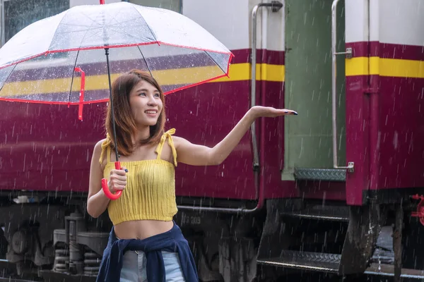 Yağmurlu günlerde tren istasyonunda şemsiye tutan çekici genç bir kadın. Yağmurlu bir günde şemsiyenin altında duran mutlu kız..