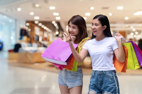 Χαρούμενη Ενθουσιασμένος Δύο Νεαρή Γυναίκα Κρατώντας Πολύχρωμες Τσάντες Ψώνια Δείχνοντας — Φωτογραφία Αρχείου