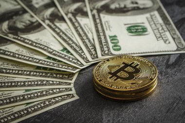 Bozuk paralar, dolarların yakınındaki siyah ahşap bir masanın üzerinde bitcoin şeklinde.