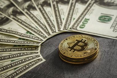 Bozuk paralar, dolarların yakınındaki siyah ahşap bir masanın üzerinde bitcoin şeklinde.