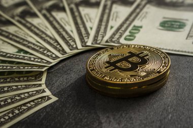 Bozuk paralar, dolarların yakınındaki siyah ahşap bir masanın üzerinde bitcoin şeklinde.