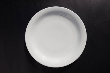 Siyah arka plan üzerine beyaz seramik yuvarlak plaka