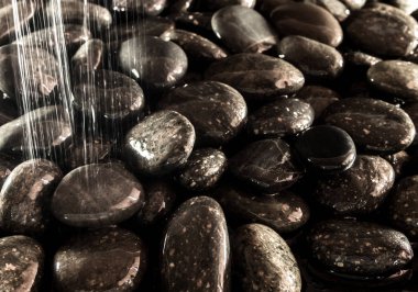 Yuvarlak kara taş şelale yanında zemin üzerine