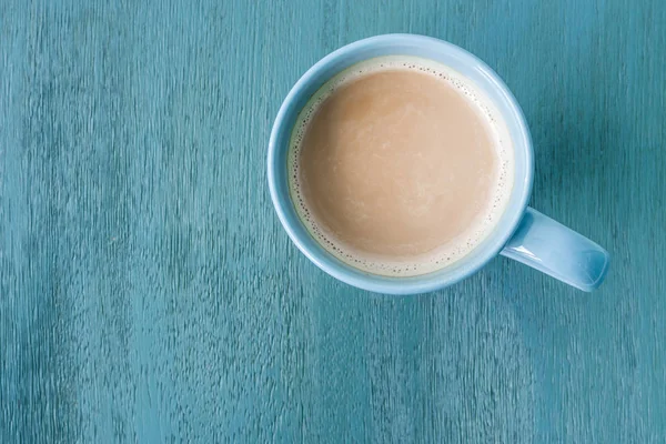 Milchkaffee in einer blauen Tasse auf pastellblauem Holzboden — Stockfoto