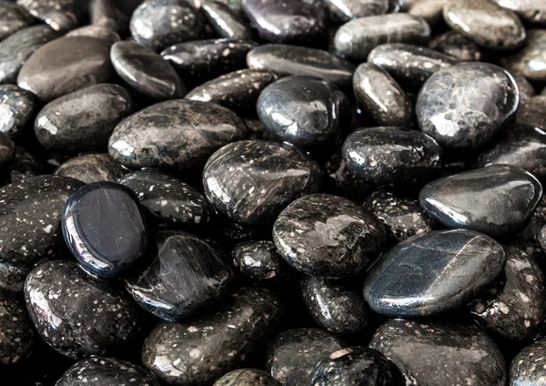 Runder schwarzer Stein auf dem Boden neben dem Wasserfall — Stockfoto