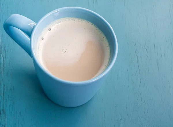 Mjölk kaffe i en blå kopp på pastellblå trägolv — Stockfoto