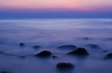 Akşam kayalık bir plajda yumuşak dalgalar