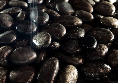 Yuvarlak kara taş şelale yanında zemin üzerine