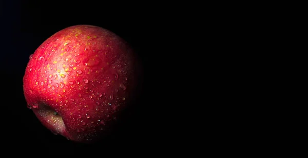 Gouttelette d'eau sur une surface brillante de pomme rouge sur fond noir — Photo