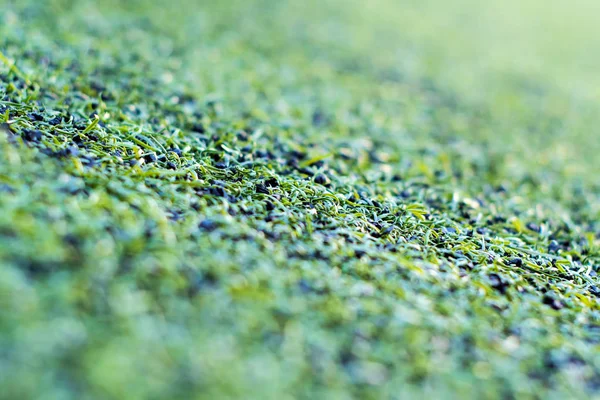 Textura de césped artificial de plástico y pellets de goma en el campo — Foto de Stock