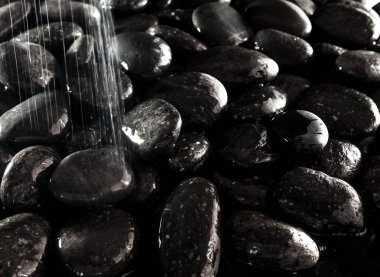 Yuvarlak kara taş şelale yanında zemin üzerine