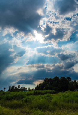 Kırsaldaki kara bulutların arkasındaki güneş ışığı huzmesi.