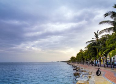 Deniz sakin ve gökyüzü kıyı bölgesinin sabahında yağmur bulutlarıyla kaplanmış.