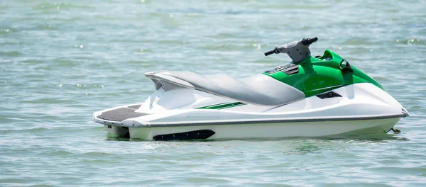 Un jetski verde blanco mientras está estacionado y flotando en el agua en un bea — Foto de Stock