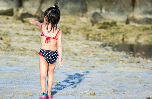 Uma criança do sexo feminino usando roupa de banho mostrando o ponto de vista traseiro — Fotografia de Stock