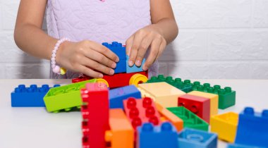 Childs'ın el üzerinde beyaz bir tabl renkli brickins lego oynarken
