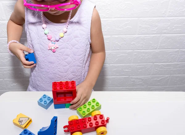 Kinderhand beim Spielen bunter Steine Lego auf einem weißen Tisch — Stockfoto