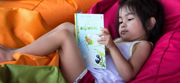 Carino asiatico femmina bambino bambino mentre la lettura di un libro e seduta — Foto Stock
