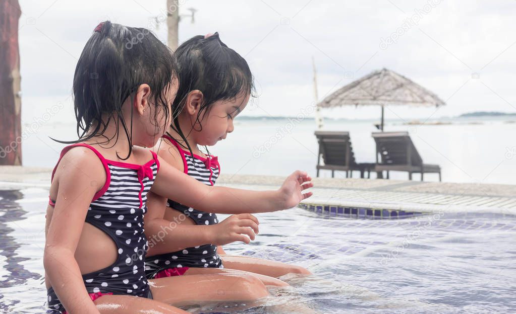 cute asian toddlers twins blurry beach background while playing 