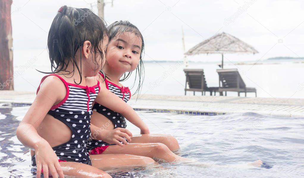 cute asian toddlers twins blurry beach background while playing 